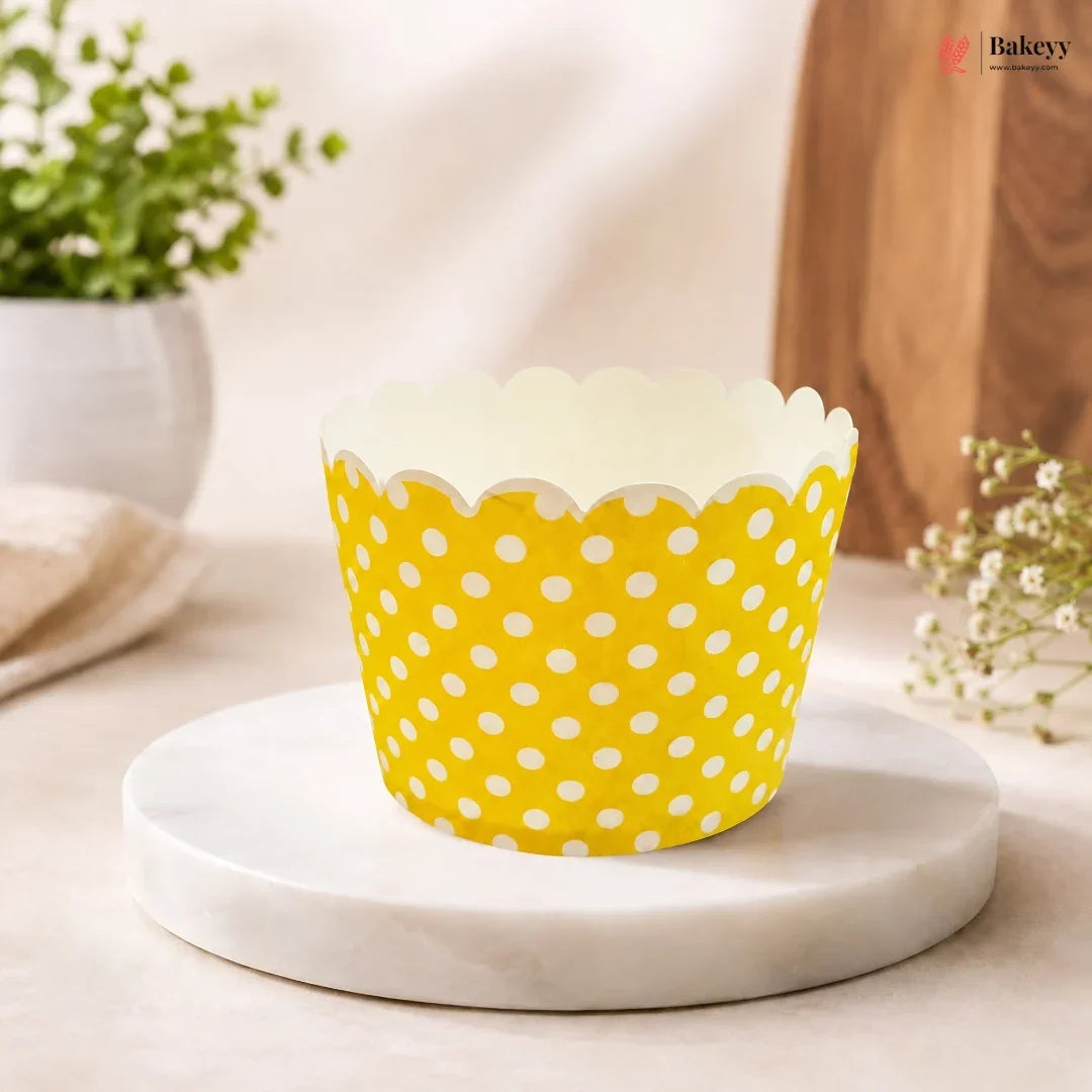 Yellow cupcake liner with white polka dots on a marble surface.