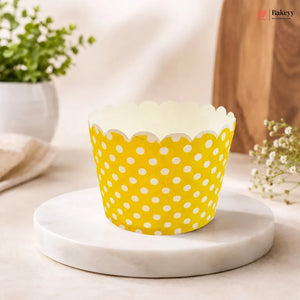 Yellow cupcake liner with white polka dots on a marble surface.