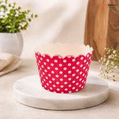 Pink cupcake liner with white polka dots on a marble surface with a blurred background