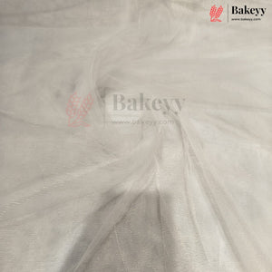 White tulle fabric draped to show its sheer, semi-transparent texture and fine mesh structure. The Bakeyy brand logo is visible in the top right corner.