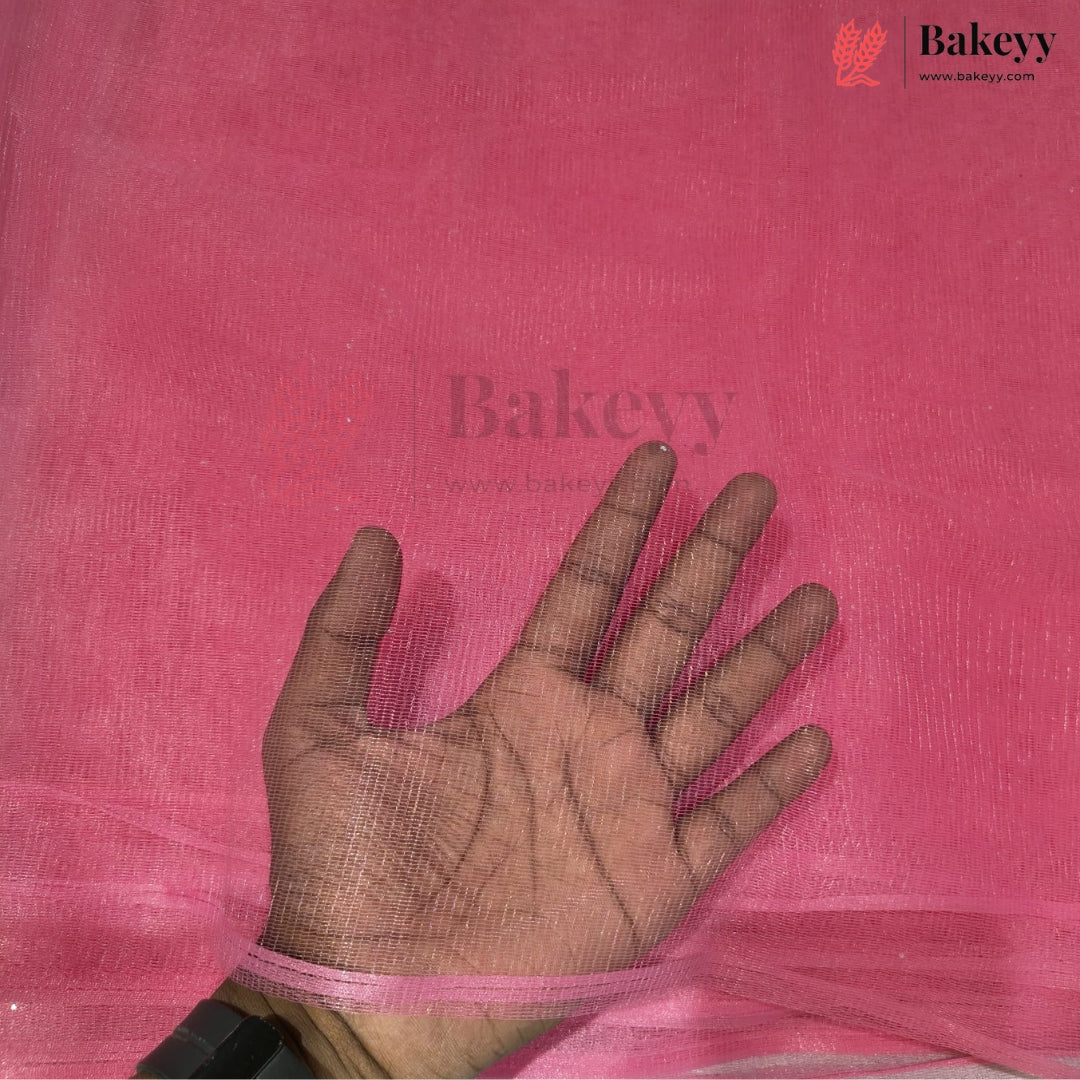 A hand is shown against a bright pink textured fabric backdrop, with a semi-transparent pink mesh sheet draped over the wrist and fingers. The Bakeyy logo is visible in the top right corner.