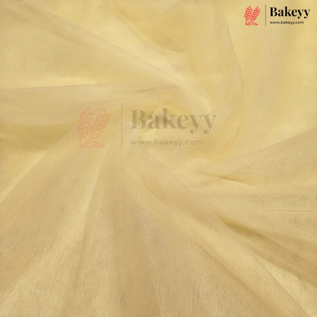 A close-up of draped pale yellow fabric with a soft, semi-sheer texture and visible weave, featuring a Bakeyy watermark logo in the center and top right corner.