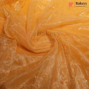 A close-up of sheer, shimmering orange tulle or organza fabric, swirled and draped to show its texture and reflective quality. The Bakeyy brand logo is visible in the top right corner.