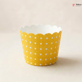 Yellow cupcake liner with white polka dots on a beige background