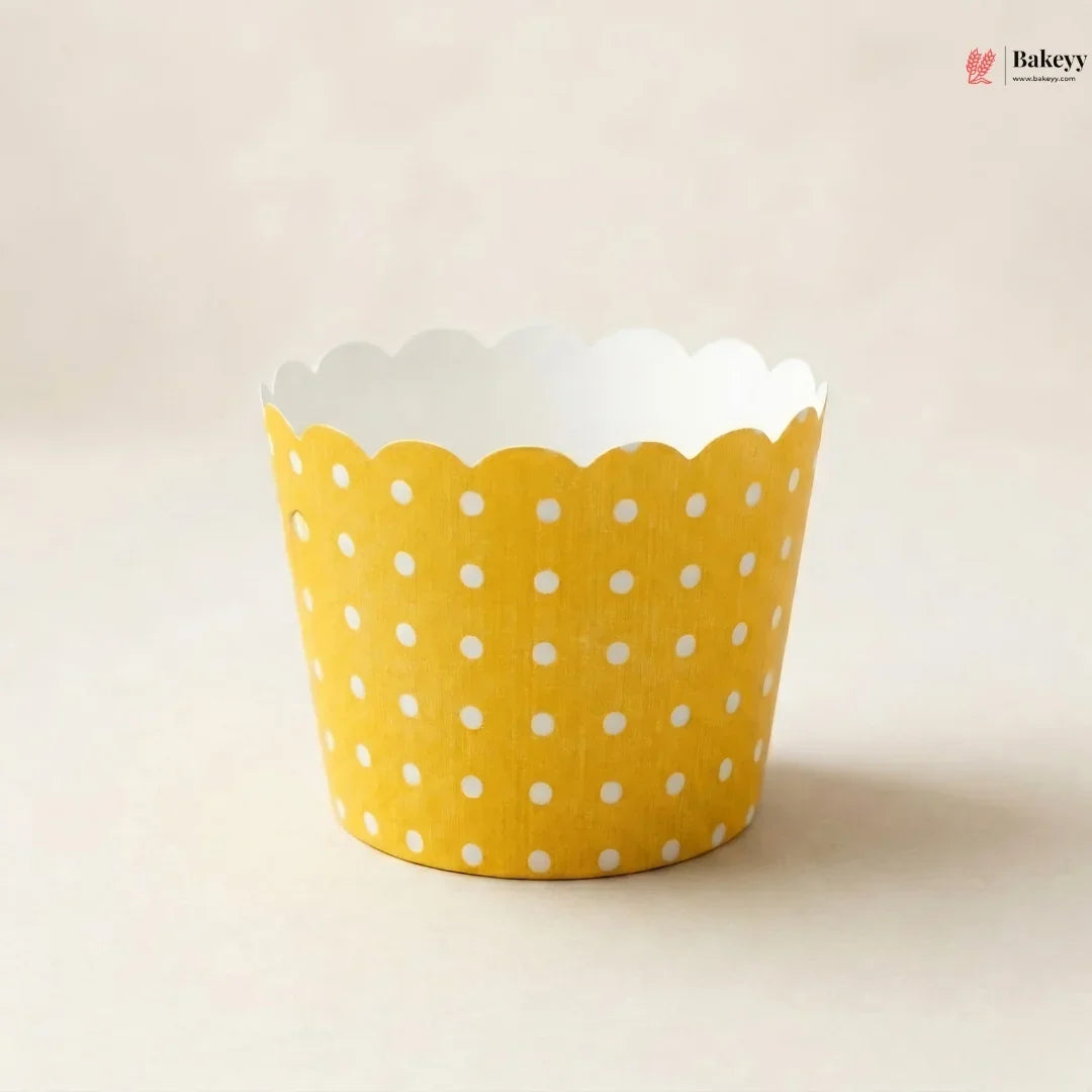 Yellow cupcake liner with white polka dots on a beige background