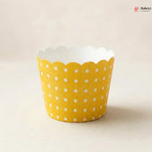 Yellow cupcake liner with white polka dots on a beige background
