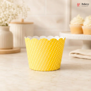 Yellow polka dot cupcake liner on a light wooden surface with a blurred background