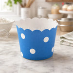 Blue paper cup with white polka dots on a marble surface, branded 'Bakeyy'.