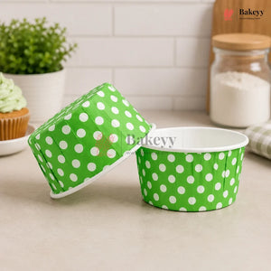 Green paper dessert cups with white polka dots on a kitchen counter, featuring the brand 'Bakeyy'.