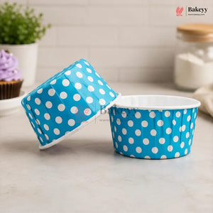 Blue paper cupcake liners with white polka dots on a kitchen counter.