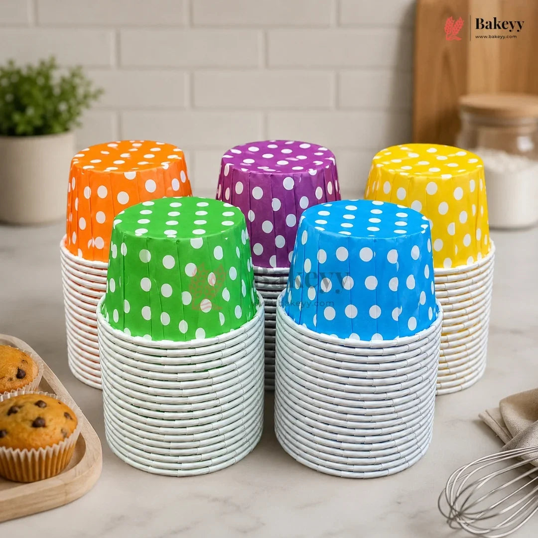 Colorful polka dot cupcake liners stacked on a kitchen counter with 'Bakeyy' branding.