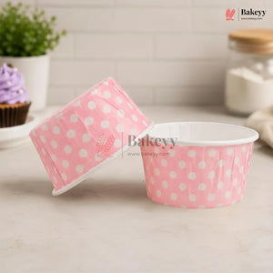 Pink paper cups with white polka dots on a kitchen counter, featuring the Bakeyy brand.