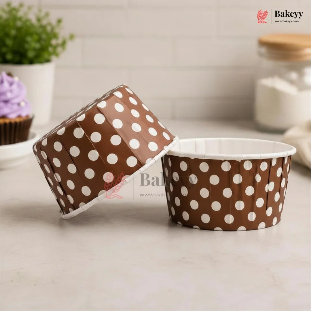 Brown paper cup with white polka dots on a light surface, with 'Bakey' branding.