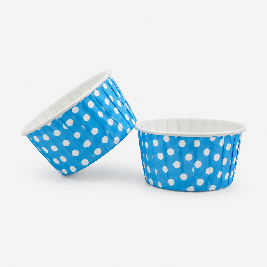 Two blue paper cups with white polka dots on a white background