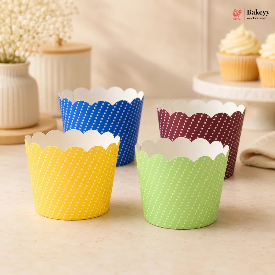 Colorful polka dot cupcake liners on a wooden surface with a blurred background of cupcakes and decor.