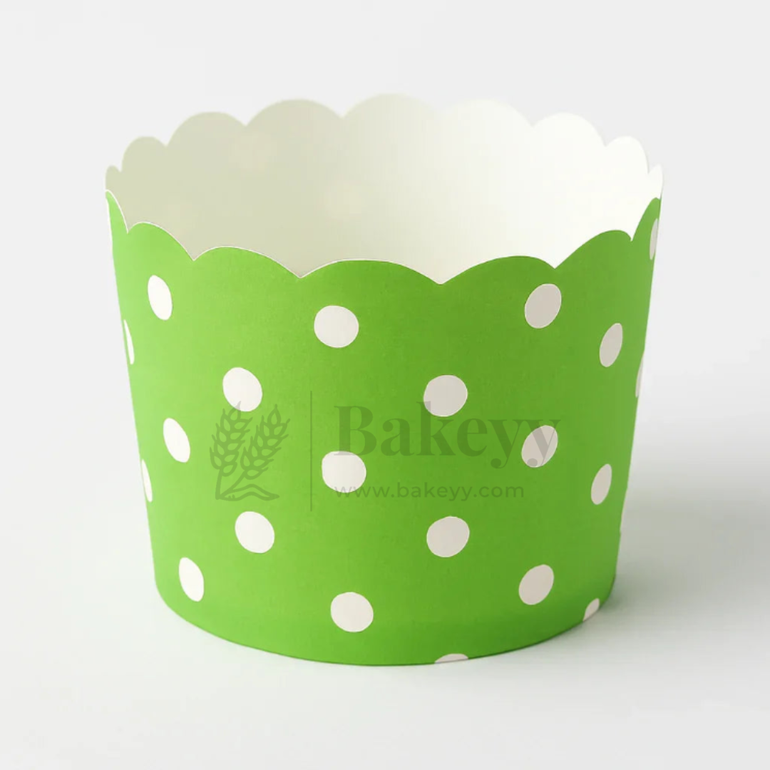 Green cupcake wrapper with white polka dots on a white background