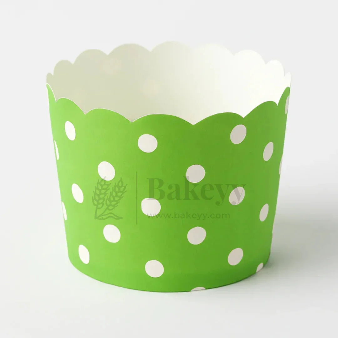 Green cupcake wrapper with white polka dots on a white background