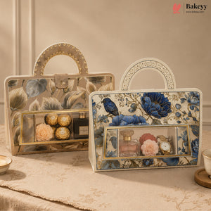 Two decorative gift boxes with floral and bird patterns, displayed on a table. One box contains Ferrero Rocher chocolates, and the other contains perfume bottles and watches.