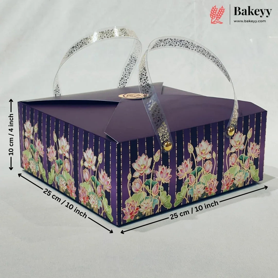 A rectangular purple bakery gift box with floral print on the sides, featuring two clear handles with silver glitter trim and gold-tone clasps. Black dimension lines and text indicate measurements of 25 cm x 25 cm x 10 cm.
