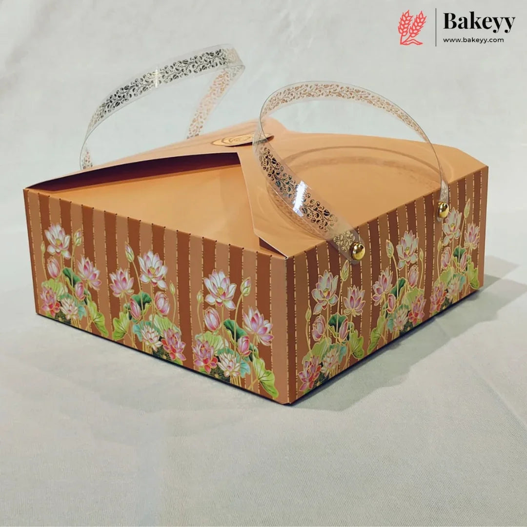 A square cardboard bakery box with a brown striped and floral patterned exterior, clear plastic handles, and a Bakeyy logo watermark in the top right corner.
