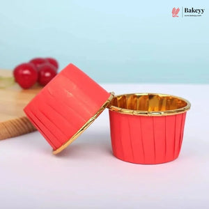 Red and gold cupcake liner with a wooden board and cherries in the background