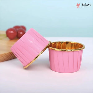 Pink cupcake liner with gold rim on a white surface, branded 'Bakey'.