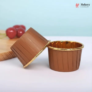 Brown cupcake liner with gold rim on a white surface, with 'Bakey' branding in the corner.