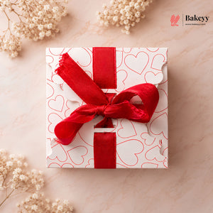 Gift box with red ribbon on a beige background with flowers
