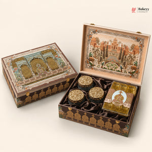 An ornate traditional Indian gift box set shown closed and open on a light beige background. The set includes a large decorated box with a detailed architectural illustration on the lid, three small round gold-lidded jars, and a square wrapped item.