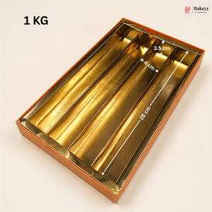 Gold metallic 4-compartment gift box with white dimension arrows and text overlays showing measurements (28 cm, 4 cm, 3.5 cm) and a '1 KG' weight label on a light beige background.