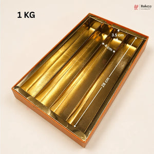 Gold metallic 4-compartment gift box with white dimension arrows and text overlays showing measurements (28 cm, 4 cm, 3.5 cm) and a '1 KG' weight label on a light beige background.