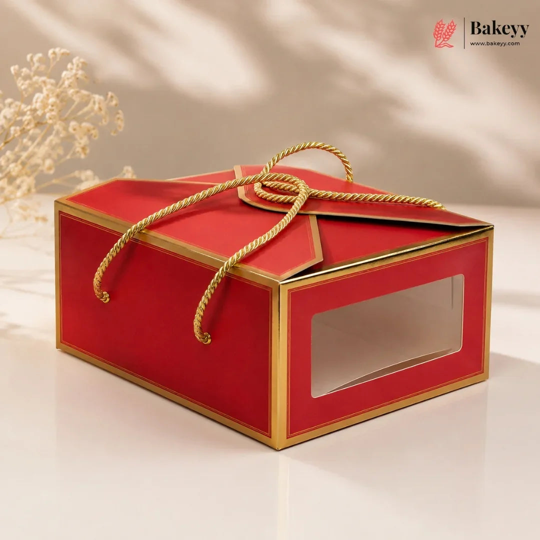 Red gift box with gold accents and a clear window on a beige background, featuring the Bakeyy brand.