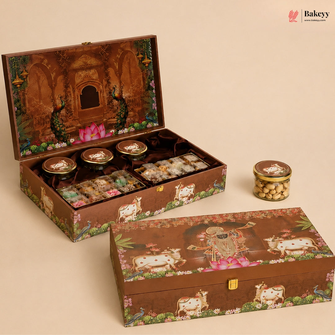 An ornate open and closed decorative gift box set on a warm beige background. The boxes feature intricate illustrations including peacocks, cows, flowers, and a central deity figure.