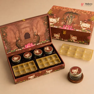 A decorative brown gift box set for sweets, shown open with several small round jars and yellow plastic tray inserts. The box lid features an illustrated temple scene with peacocks and pink lotus flowers, and the closed box in the background shows cows and floral motifs.