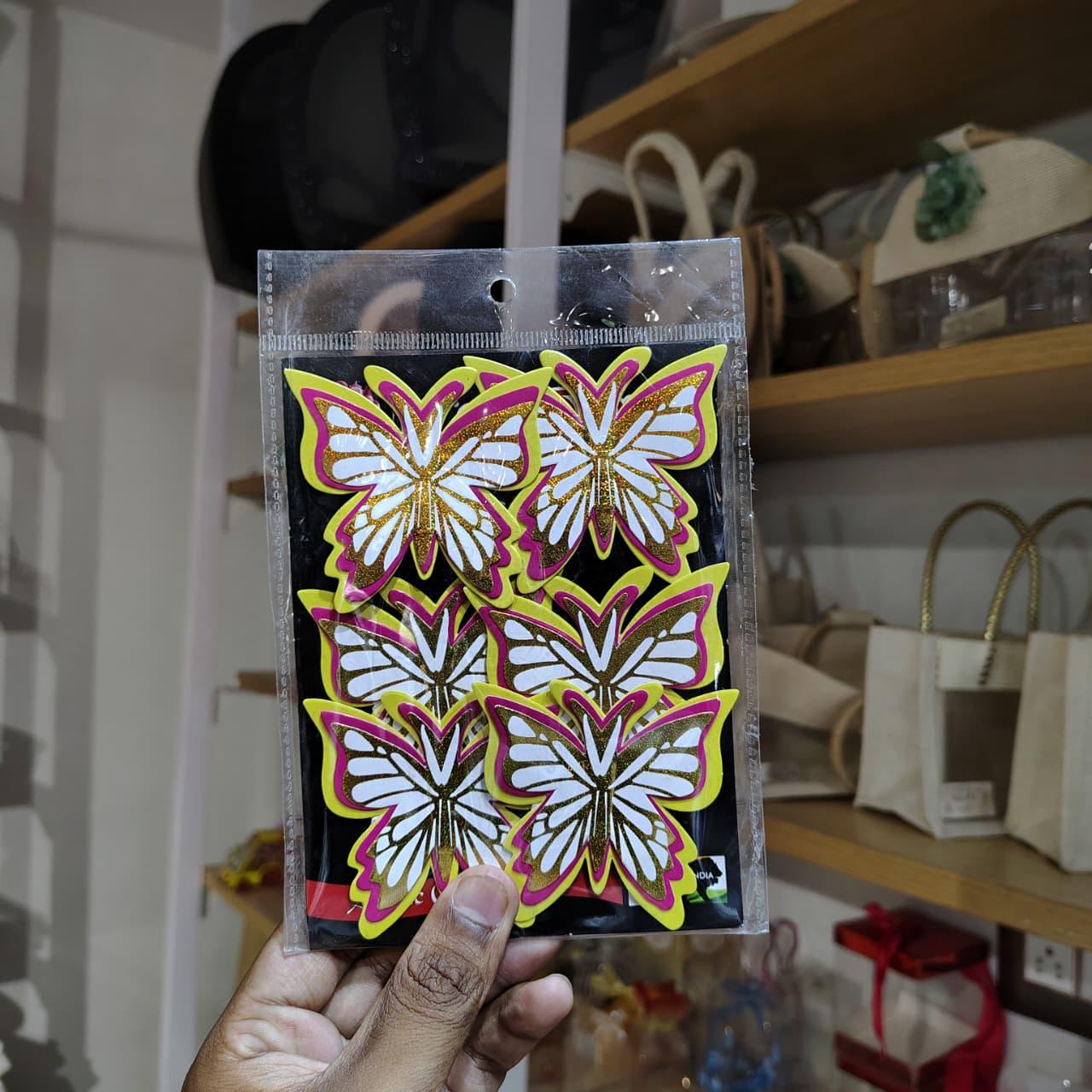 Packaged butterfly stickers held in front of a store shelf with bags and products.