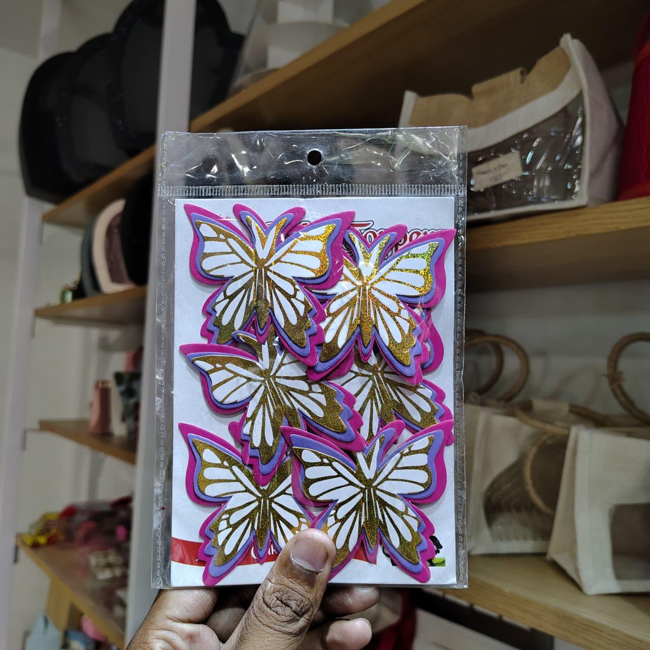 Packaged butterfly decorations held by a hand with a blurred background