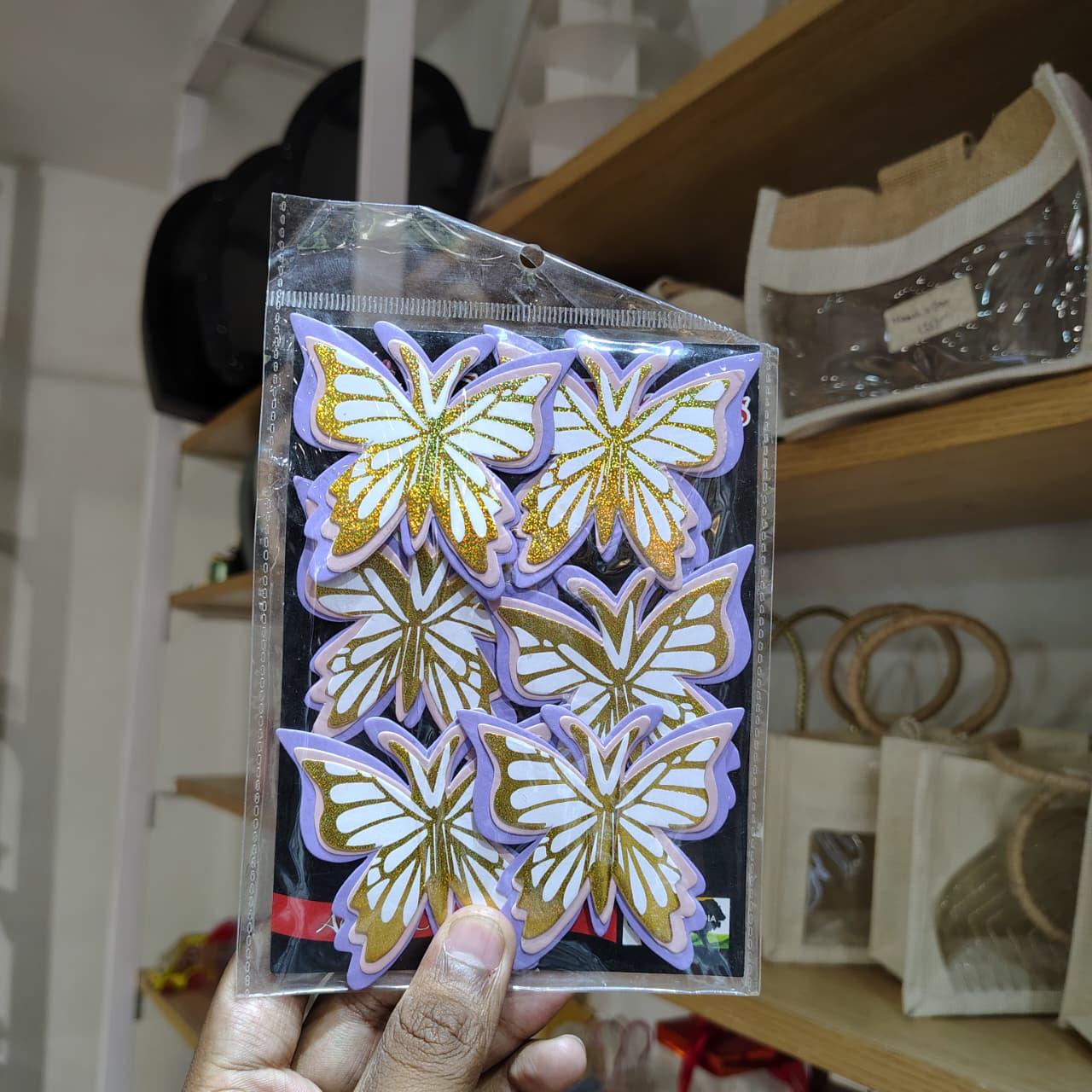 Packaged butterfly-shaped decorative items held by a hand with a blurred background