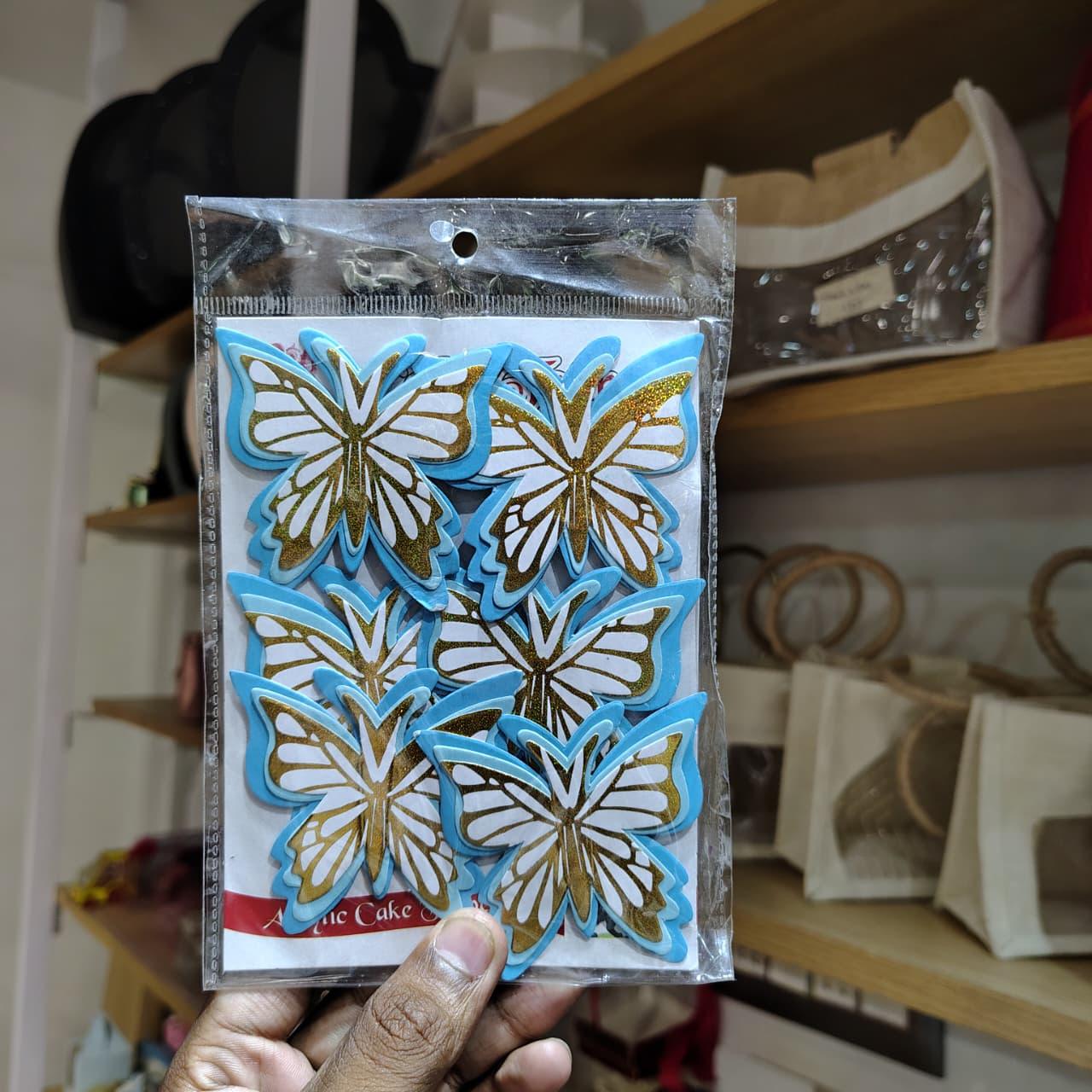 Packaged butterfly-shaped clear stamps held in front of a blurred indoor background
