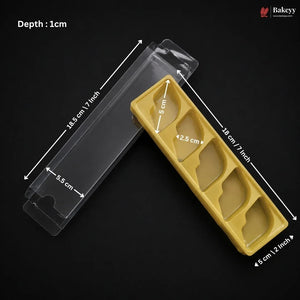 A clear plastic pastry tray shown with overlaid dimension arrows and text indicating depth and measurements, on a black background. A yellow insert tray with four compartments is placed beside it for scale/context.