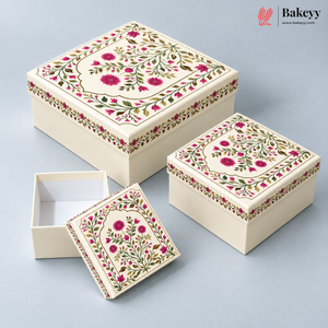 Three cream-colored decorative gift boxes with floral patterns, including one open box and two closed boxes with matching lids, displayed on a light gray background. The Bakeyy logo is visible in the top right corner.