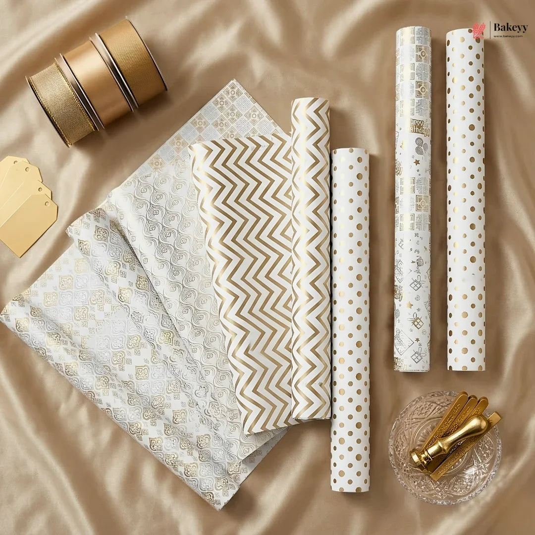 Collection of gold and white patterned gift wrap on a beige fabric background