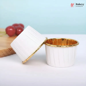 White cupcake liner with gold rim on a white surface, with 'Bakeey' brand logo in the corner.