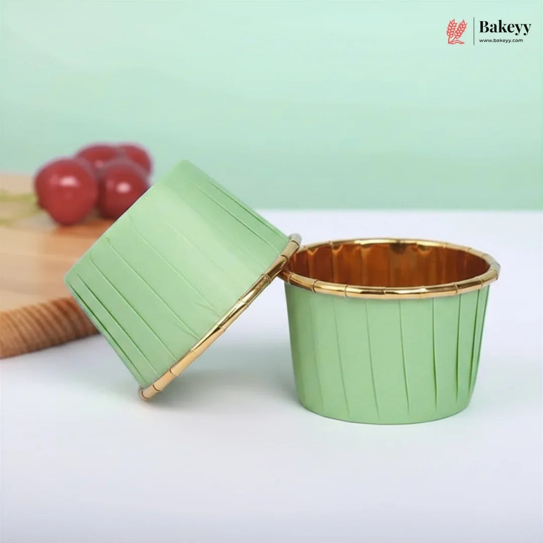 Green cupcake liner with gold rim on a white surface, branded 'Bakey'.
