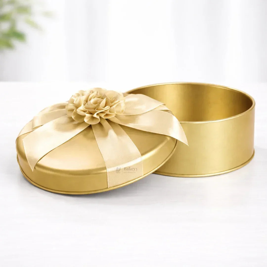 Premium round gold tin box with ribbon and flower, ideal for gift packaging from Bakeyy