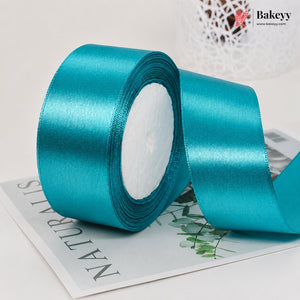 Turquoise satin ribbon roll on a magazine with 'Bakeyy' branding.