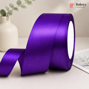 Purple satin ribbon roll on a light surface with a blurred background