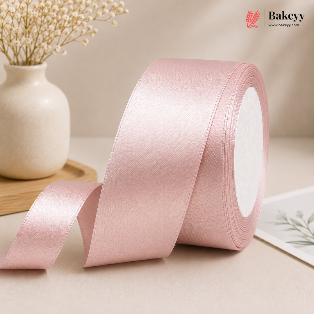 Roll of pink satin ribbon with a vase and card in the background, featuring the Bakeyy brand.