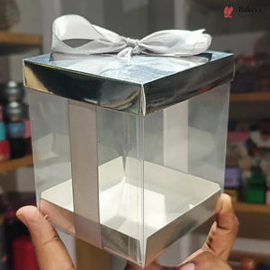 Clear gift box with a silver bow held by a hand against a blurred background