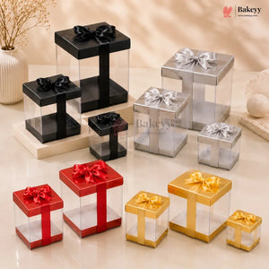 Collection of transparent gift boxes with colored ribbons and bows on a beige surface, featuring the Bakeyy brand.