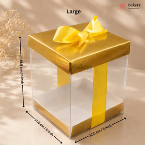 Gold gift box with clear side panel and measurements on a beige background